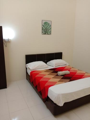a bedroom with a bed with a checkered blanket at Ulfah Mersing الفة in Mersing