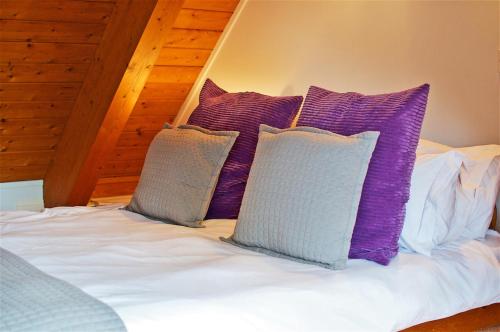 a bed with purple and white pillows on it at Northlands Farm Superior Chalet 3 in Chichester