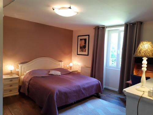 ein Schlafzimmer mit einem Bett mit einer lila Decke und einem Fenster in der Unterkunft Moulin de la Fleuristerie in Orges