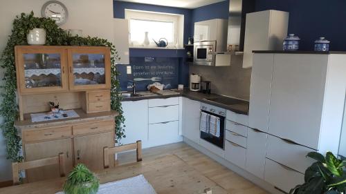 een keuken met witte kasten en een fornuis met oven bij viaDolceVita - Blaue Gästewohnung in Lana