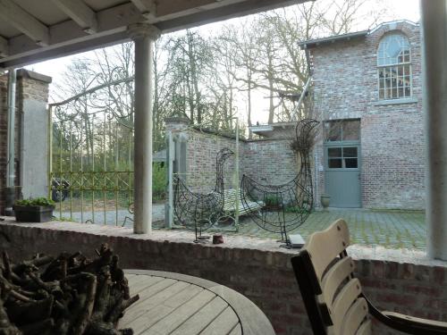 a patio with a table and chairs and a building at Eremyten Hof in Evergem