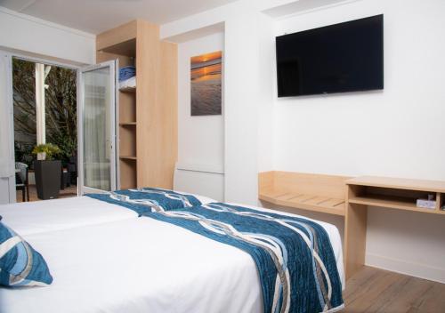 a bedroom with a white bed and a tv at Hotel Les Dunes in La Tranche-sur-Mer