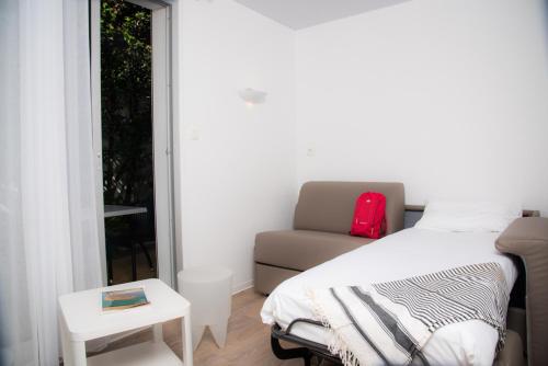 a bedroom with a bed and a couch and a window at Hotel Les Dunes in La Tranche-sur-Mer