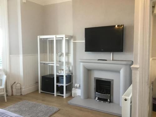 a living room with a fireplace with a flat screen tv over it at Cara Guesthouse in Whitley Bay