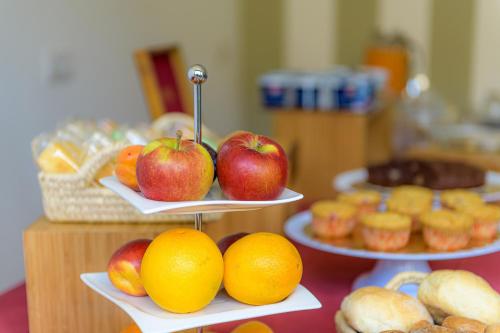 a table with three plates of apples and oranges and muffins at Hotel La Rotonda in Tirano