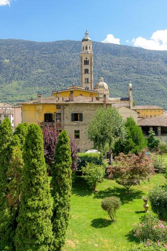 an old building with a clock tower in a garden at Hotel La Rotonda in Tirano