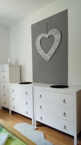 a bedroom with white dressers and a heart on the wall at Landhaus Tirol in Presseggersee