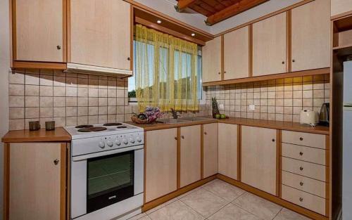 a kitchen with wooden cabinets and a stove top oven at Tsiolis Studios & Apartments in Tsilivi