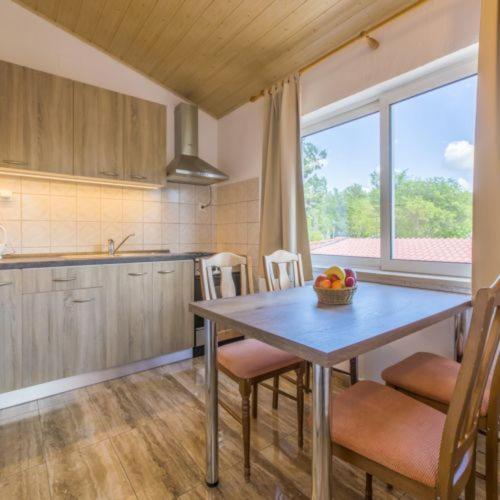 a kitchen with a table with a bowl of fruit on it at Apartmani s dvije spavaće sobe 4 osobe in Selce