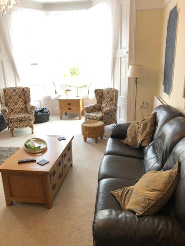 a living room with a leather couch and a coffee table at Milton Lodge in Weston-super-Mare