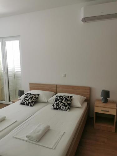 a large white bed with two pillows on it at Apartmani Kronjac in Milna