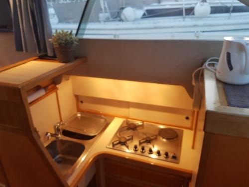 Il comprend une cuisine équipée d'une cuisinière et d'un évier avec une fenêtre. dans l'établissement BOAT APPART TITANIC Cherbourg motor yacht à quai ROSE STAR, à Cherbourg en Cotentin