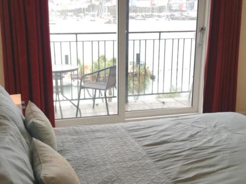 a bedroom with a bed and a window with a balcony at Riverside 2 in Dartmouth