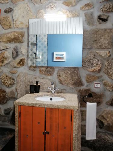 a bathroom with a sink and a stone wall at Casa da Montanha in Rebordões