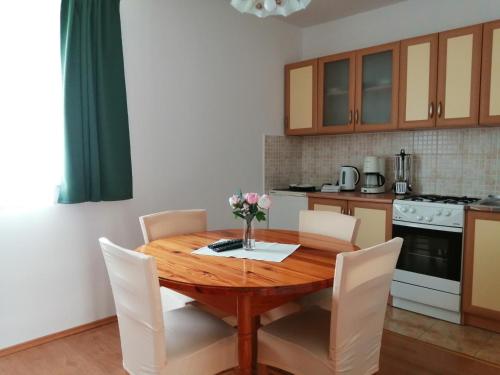 cocina con mesa de madera y sillas blancas en Apartments Jure, en Smoljanac