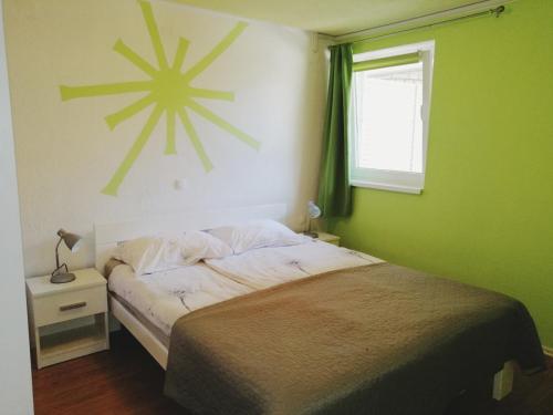 a green bedroom with a bed and a window at Apartmaji Iris Kobarid in Kobarid