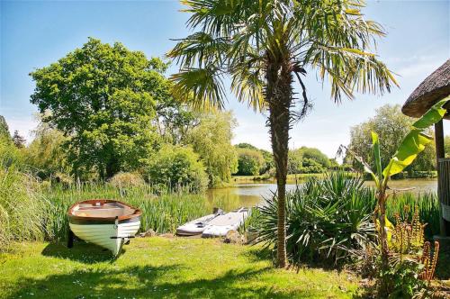 a boat sitting on the grass next to a lake at Northlands Farm Superior Chalet 3 in Chichester
