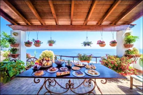 una tavola di cibo su un patio con l'oceano sullo sfondo di B&B Villa Antica a Ischia