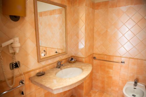 La salle de bains est pourvue d'un lavabo, d'un miroir et de toilettes. dans l'établissement Hotel Ostello Settecolli Sport, à Filottrano