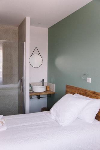 a bedroom with a bed and a bathroom with a sink at L'Argalyde Esprit Pyrénées Wellness & Cycling in Ayzac-Ost