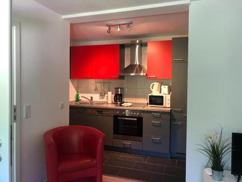 a kitchen with red cabinets and a red chair at Ferienhof Kröger in Bielefeld