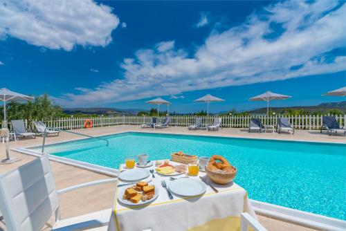 a table with food on it next to a swimming pool at Leonidas Resort in Ermioni