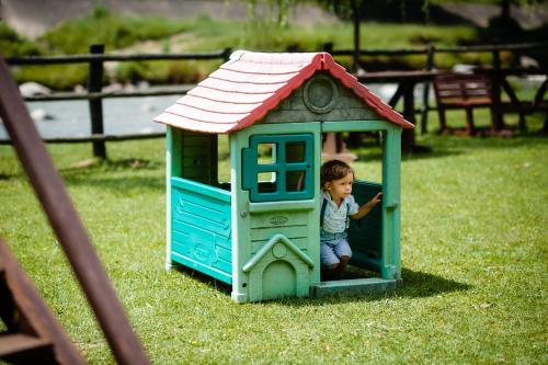 a little boy is playing in a toy house at Pensiunea Trei Ponei in Corbeni