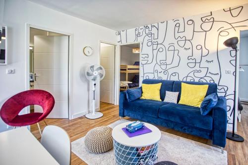 a living room with a blue couch and a red chair at Esprit BD & Confort à Angoulême - Comme à la Maison in Angoulême