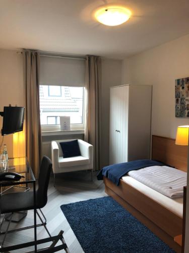 um quarto com uma cama, uma cadeira e uma janela em bensons hotel em Aachen