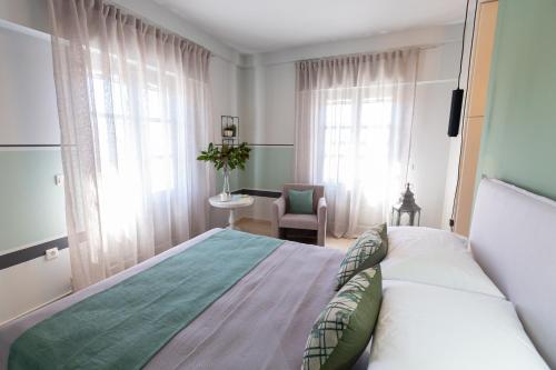 a bedroom with a bed and a chair and windows at Magnolia - Apartment in Kalamata in Kalamata