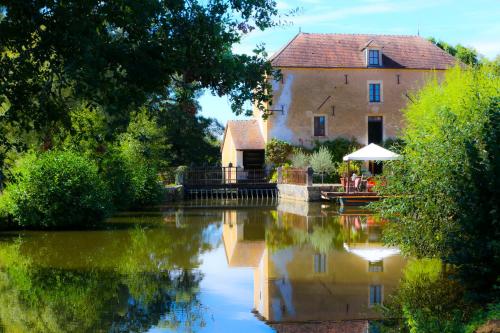 a building next to a river with a reflection in the water at Chambre Coton au Moulin de gâteau in Saint-Pierre-les-Étieux