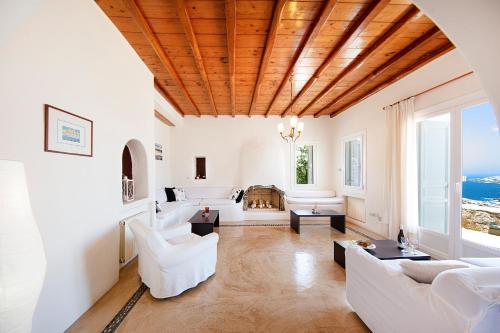 Agios Sostis MykonosにあるVillas Kappasの白い家具と木製の天井が備わるリビングルーム