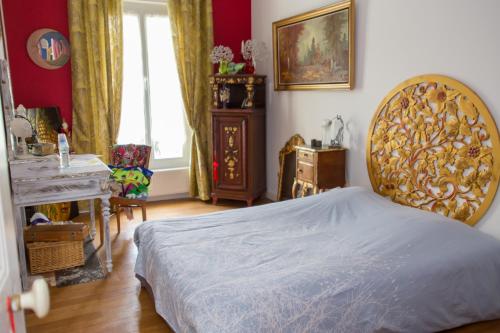 Schlafzimmer mit einem Bett mit einem goldenen Kopfteil in der Unterkunft Le Madrigal in Mamers
