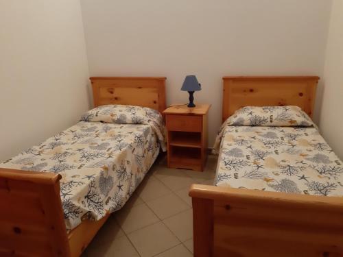 a bedroom with two beds and a lamp on a night stand at Villa Nausica in Capo Vaticano