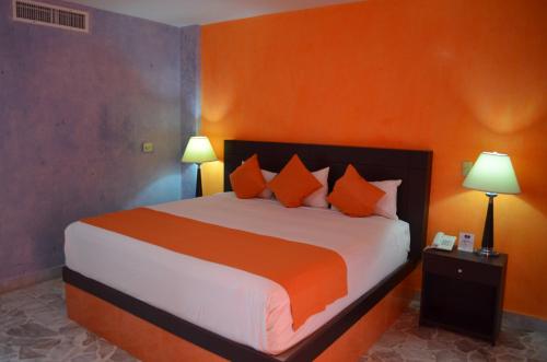 a bedroom with a large bed with orange walls at Hotel María Eugenia in Tuxtla Gutiérrez