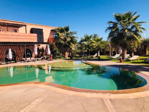 Azib Oulad Lâdem的住宿－紅寶石東方旅館，棕榈树建筑前的游泳池