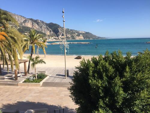 a beach with palm trees and the ocean at ibis budget Menton Bord de Mer in Menton