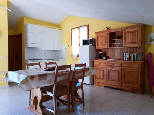 a kitchen with a table and chairs and a white refrigerator at Chia Zeffiro in Chia