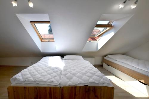 a attic bedroom with a bed and two windows at ubytovanie-stiavnica in Banská Štiavnica