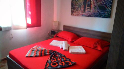 a red bed with red sheets and towels on it at ATHINA'S HOUSE in Nea Potidaea