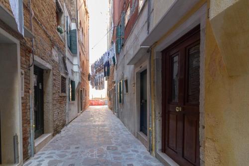 an empty alley with a brown door and buildings at Veneziacentopercento Arsenale Apartment in Venice