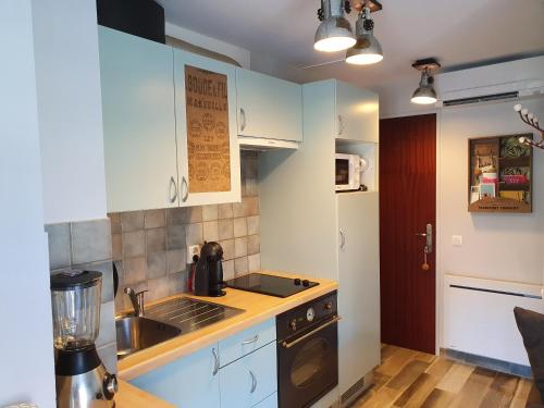 - une cuisine avec des placards bleus, un évier et une cuisinière dans l'établissement Studio accès direct à la plage, à La Londe-les-Maures