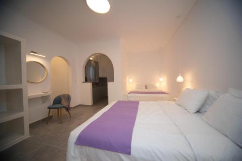 a hotel room with a large bed and a chair at Markakis Studios Fira Town in Fira