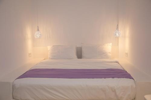a bedroom with a white bed with two lights at Markakis Studios Fira Town in Fira