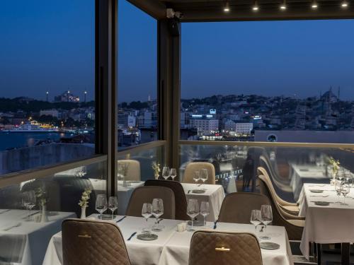 Un restaurante con mesas y sillas y vista a la ciudad. en Azzap Hotel Galata, en Estambul