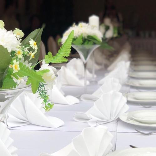 a long white table with white plates and flowers at Folwark Nadmorska Ostoja in Mechelinki