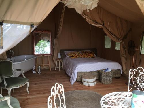 1 dormitorio con cama y bañera en una tienda en Les Toiles de La Tortillère tentes luxes safari lodge glamping insolite, en Marçay