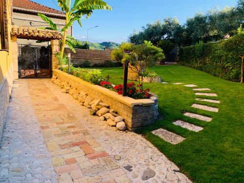 a garden with a stone retaining wall and flowers at Flowery House in Miglianico