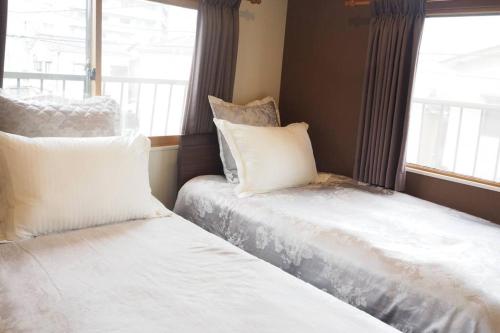 2 letti posti accanto a una finestra in una stanza di Harbour Inn & Suites 201 a Niigata