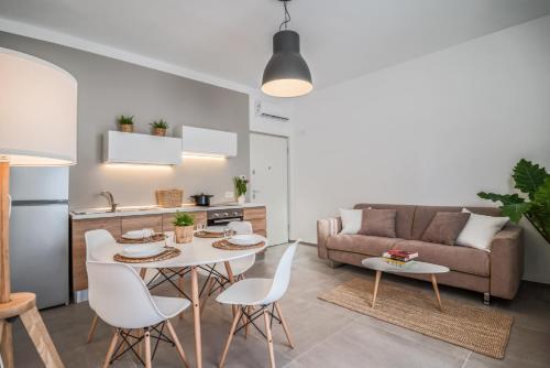 een woonkamer met een tafel en stoelen en een bank bij LE CORALLINE in Meta